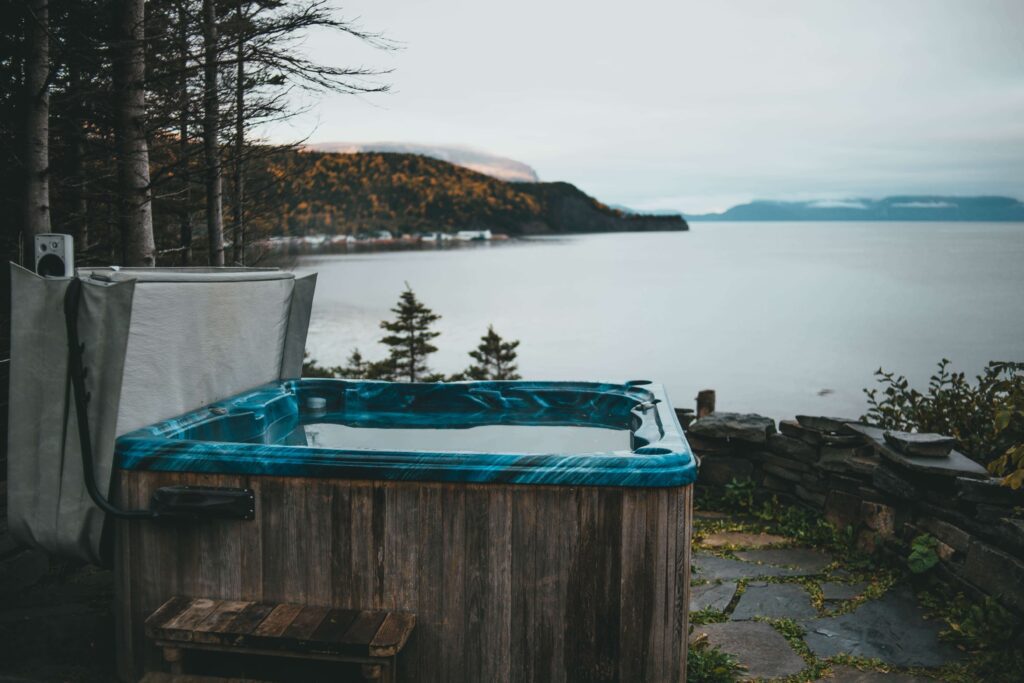 A wooden hot tub sitting in front of a body of water